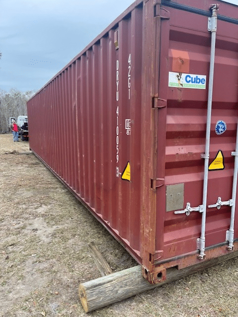 A large red shipping container placed on a grassy field, ready for transport or storage solutions.